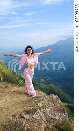 Girl enjoys a mountain view while standing on a 63299998