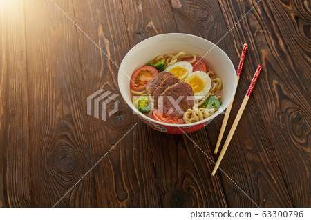 Asian noodle soup with vegetables, egg, beef and chopsticks on wooden background and copy space Asian noodle soup with vegetables, egg, beef and chopsticks on wooden background and copy space 63300796