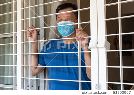Anxious Chinese man with face mask self isolate at home Anxious Chinese man with face mask self isolate at home 63300997