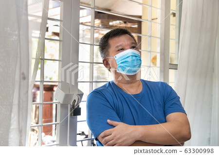 Anxious Chinese man with face mask self isolate at home Anxious Chinese man with face mask self isolate at home 63300998