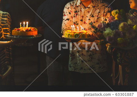 Short in low light family celebrating birthday to their mother with cake. 63301887