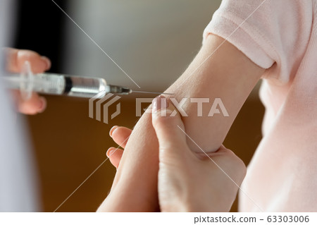 Female doctor making vaccination prick to little patient. Female doctor making vaccination prick to little patient. 63303006