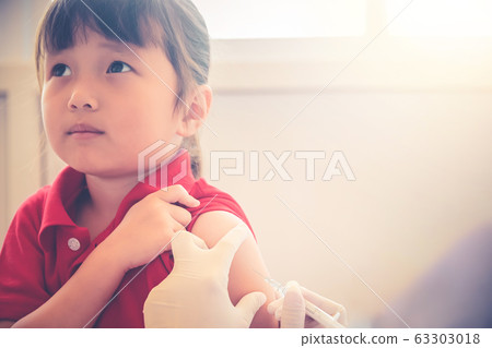 Asian Little child having Injection,Close-up Doctor injecting vaccination to arm of little girl vaccine injection in hospital for immunization afraid face and looking up ,health and medical concept 63303018