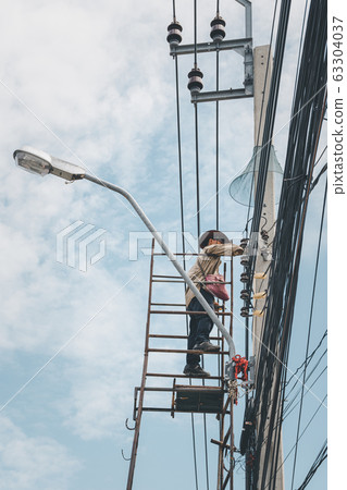 Electricians risk working install electric line 63304037