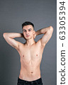 Sexy young man posing in studio. Gray background 63305394