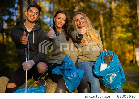 Smiling volunteers showing thumbs up at park Smiling volunteers showing thumbs up at park 63305686