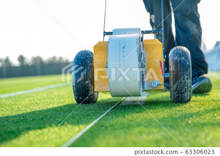 drawn white lines on the football field with white paint on the grass using a special machine before a game 63306023