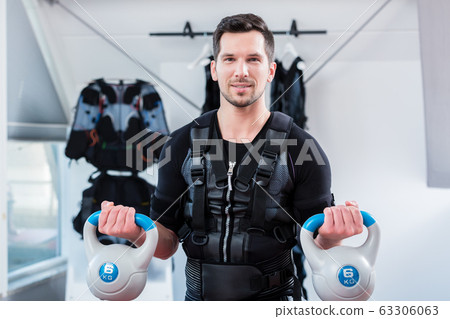 Strong man in ems gym doing fitness training with weights Strong man in ems gym doing fitness training with weights 63306063