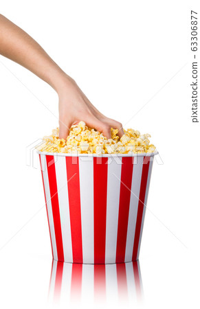 Woman hand picking popcorn from striped bucket isolated on white background Woman hand picking popcorn from striped bucket isolated on white background 63306877