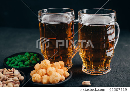 Nuts, pistachios and corn with two mugs of lager Nuts, pistachios and corn with two mugs of lager 63307519