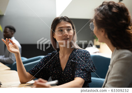 Serious Asian businesswoman discussing project with colleague at workplace 63309232