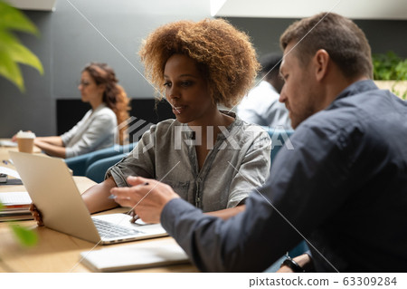 Serious businessman, mentor teaching African American businesswoman, trainee Serious businessman, mentor teaching African American businesswoman, trainee 63309284