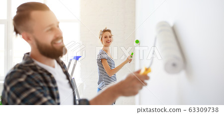 Happy couple painting wall together. Happy couple painting wall together. 63309738