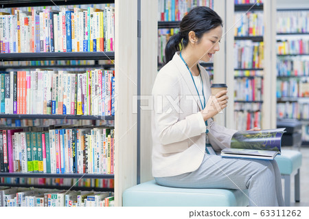 Middle-aged woman looking at photo book in library 63311262