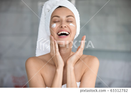 Joyful lady using professional skincare product alone in bathroom. Joyful lady using professional skincare product alone in bathroom. 63312782