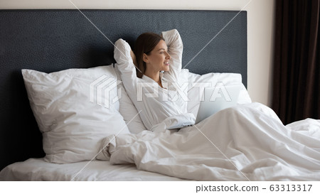 Happy woman enjoying good morning time in bed with computer. 63313317