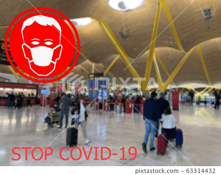 Stop COVID-19. Warning medical protection mask sign on Check-in and departure hall at one of the European airports background. 63314432