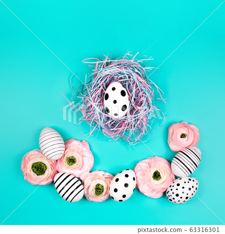 Decorative bird nest with creative graphic eggs and ranunculus flowers. 63316301