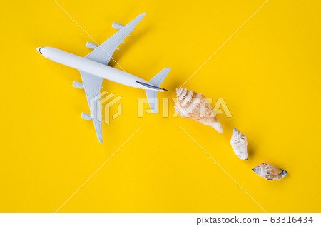 Summer travel concept. Decorative airplane and seashells on yellow background. Summer travel concept. Decorative airplane and seashells on yellow background. 63316434