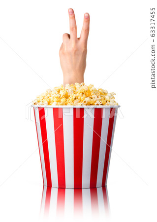 Female hand sticks out of a bucket with popcorn isolated on white background Female hand sticks out of a bucket with popcorn isolated on white background 63317455