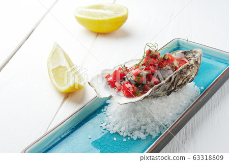 Fresh Oysters with tomato and herbs on the blue plate, table with oysters, lemon and salt. Table top view. Healthy sea food. Fresh raw Oyster dinner in restaurant. Gourmet food. Fresh Oysters with tomato and herbs on the blue plate, table with oysters, lemon and salt. Table top view. Healthy sea food. Fresh raw Oyster dinner in restaurant. Gourmet food. 63318809