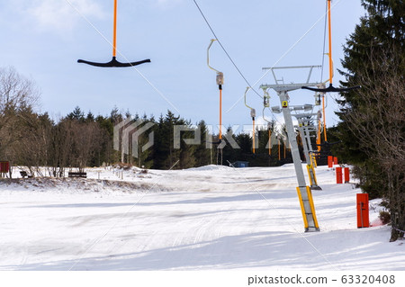Stopped t-bar surface lift on empty ski slope, end of ski season concept, disappearing snow, sunny winter or spring day, Horni Mala Upa, Krkonose mountains, Czech Republic Stopped t-bar surface lift on empty ski slope, end of ski season concept, disappearing snow, sunny winter or spring day, Horni Mala Upa, Krkonose mountains, Czech Republic 63320408