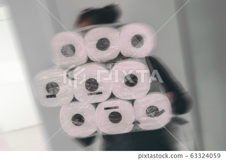 Coronavirus shopping frenzy at store woman carrying many packages of toilet paper in panic buying afraid of shortage in store. Motion blur Coronavirus shopping frenzy at store woman carrying many packages of toilet paper in panic buying afraid of shortage in store. Motion blur 63324059