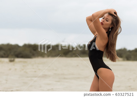 Sensual slim female in black swimsuit on beach Sensual slim female in black swimsuit on beach 63327521