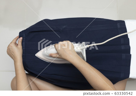 Woman hand ironing clothes blue student, High Woman hand ironing clothes blue student, High 63330542