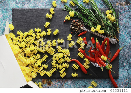 Uncooked pasta on a stone background. With seasonings and spices, spicy chili peppers. Uncooked pasta on a stone background. With seasonings and spices, spicy chili peppers. 63331111