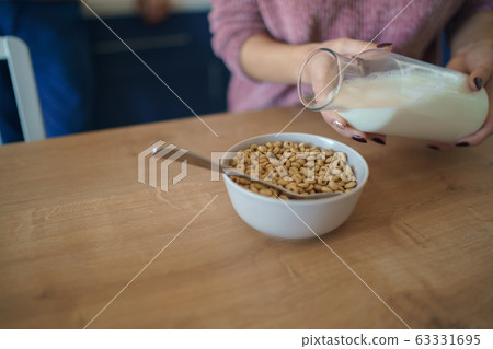 Pouring fresh creamy milk into a bowl of cereal round loops. Healthy breakfast concept 63331695