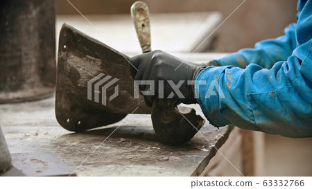 Concrete industry - man worker cleaning the form for concrete casting out from the leftovers Concrete industry - man worker cleaning the form for concrete casting out from the leftovers 63332766