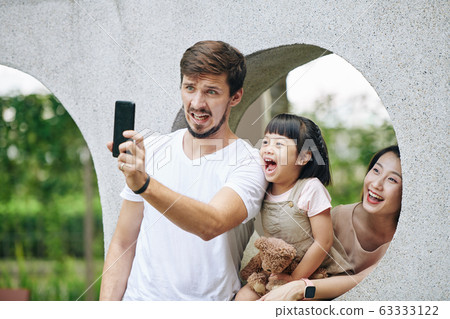 Family taking funny photo in park Family taking funny photo in park 63333122