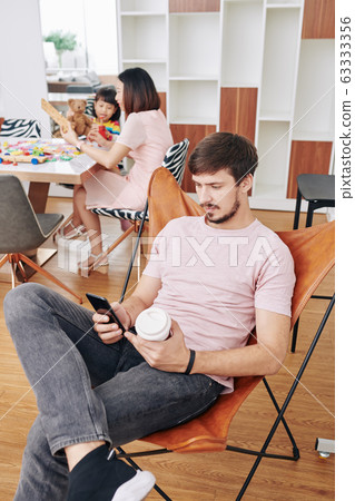 Father spending time with smartphone Father spending time with smartphone 63333356