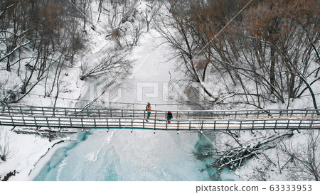Two young women standing on the snowy bridge in the winter forest Two young women standing on the snowy bridge in the winter forest 63333953