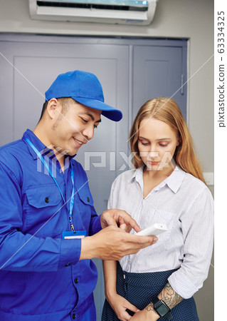 Technician explaining work of air conditioner 63334325