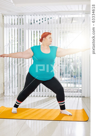 Plus size woman in warrior pose Plus size woman in warrior pose 63334618