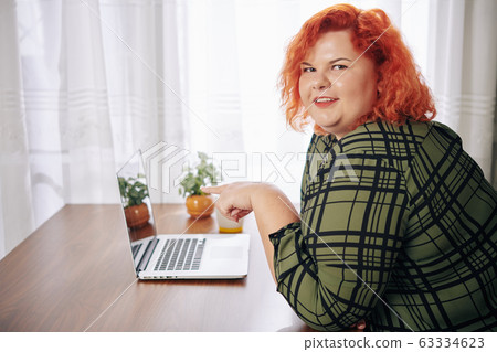 Overweight woman pointing at screen 63334623