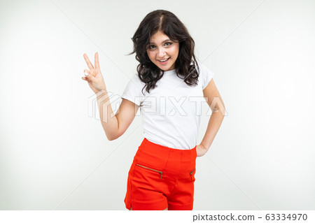 energetic girl in a white T-shirt shows two fingers on a white background energetic girl in a white T-shirt shows two fingers on a white background 63334970