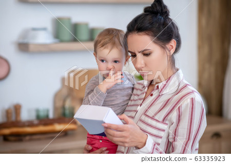 Mom reading medicine instruction, daughter poking nose Mom reading medicine instruction, daughter poking nose 63335923