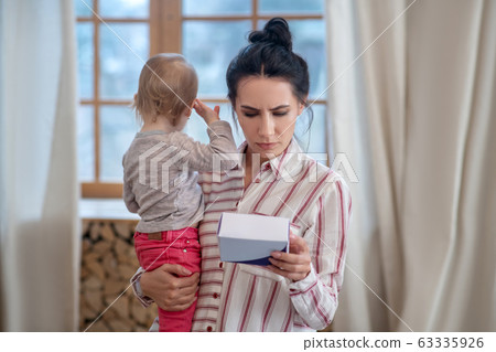 Mom holding her daughter, reading medicine instruction Mom holding her daughter, reading medicine instruction 63335926