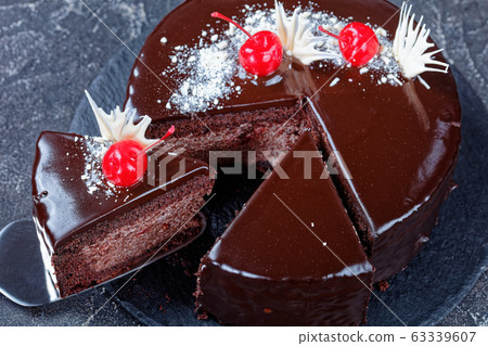 Cutted chocolate cake with cherries on top 63339607