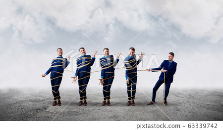 Angry businessman pulls with a rope tied himself. 63339742