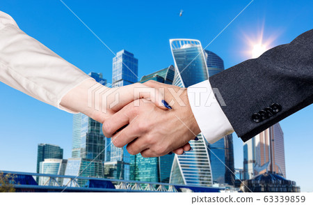 Handshake of business people over city buildings background Handshake of business people over city buildings background 63339859
