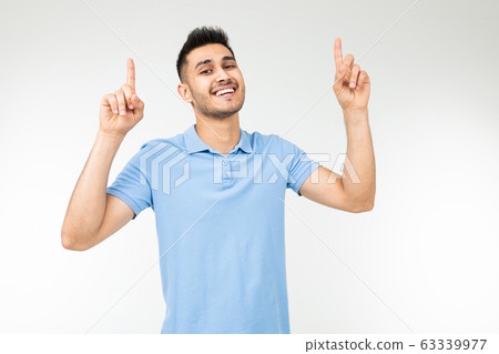 handsome caucasian man in a blue t-shirt with holding hands offers to buy something on a white handsome caucasian man in a blue t-shirt with holding hands offers to buy something on a white 63339977
