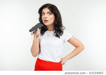 girl carefully talking on the phone over the speakerphone on a white background girl carefully talking on the phone over the speakerphone on a white background 63339987