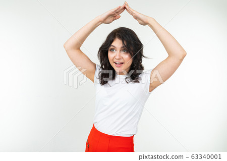 girl shows with her hands a roof over her head on a white studio background 63340001