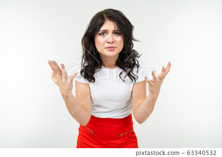 indignant brunette girl in a white tank top fed up on a white studio background indignant brunette girl in a white tank top fed up on a white studio background 63340532