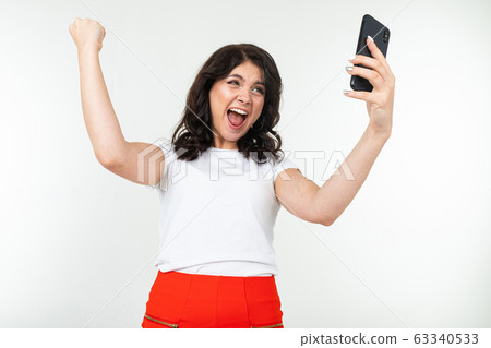 successful brunette young woman with a smartphone in her hands on a white background with copy space 63340533