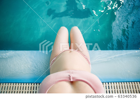 Pregnant woman with big belly sitting on poolside Pregnant woman with big belly sitting on poolside 63340536